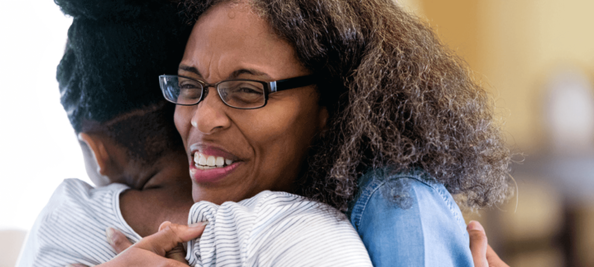 Woman wearing glasses hugging someone excitedly