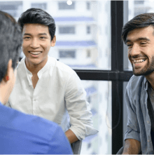 Three men sitting in a circle together laughing 