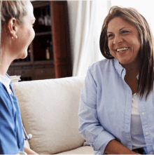 Two woman sitting on a couch smiling together